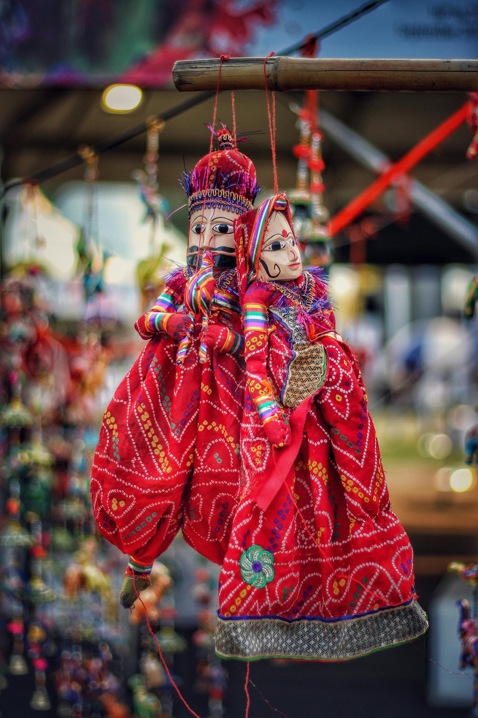 Vibrant Indian puppets with intricate designs hanging in a market.