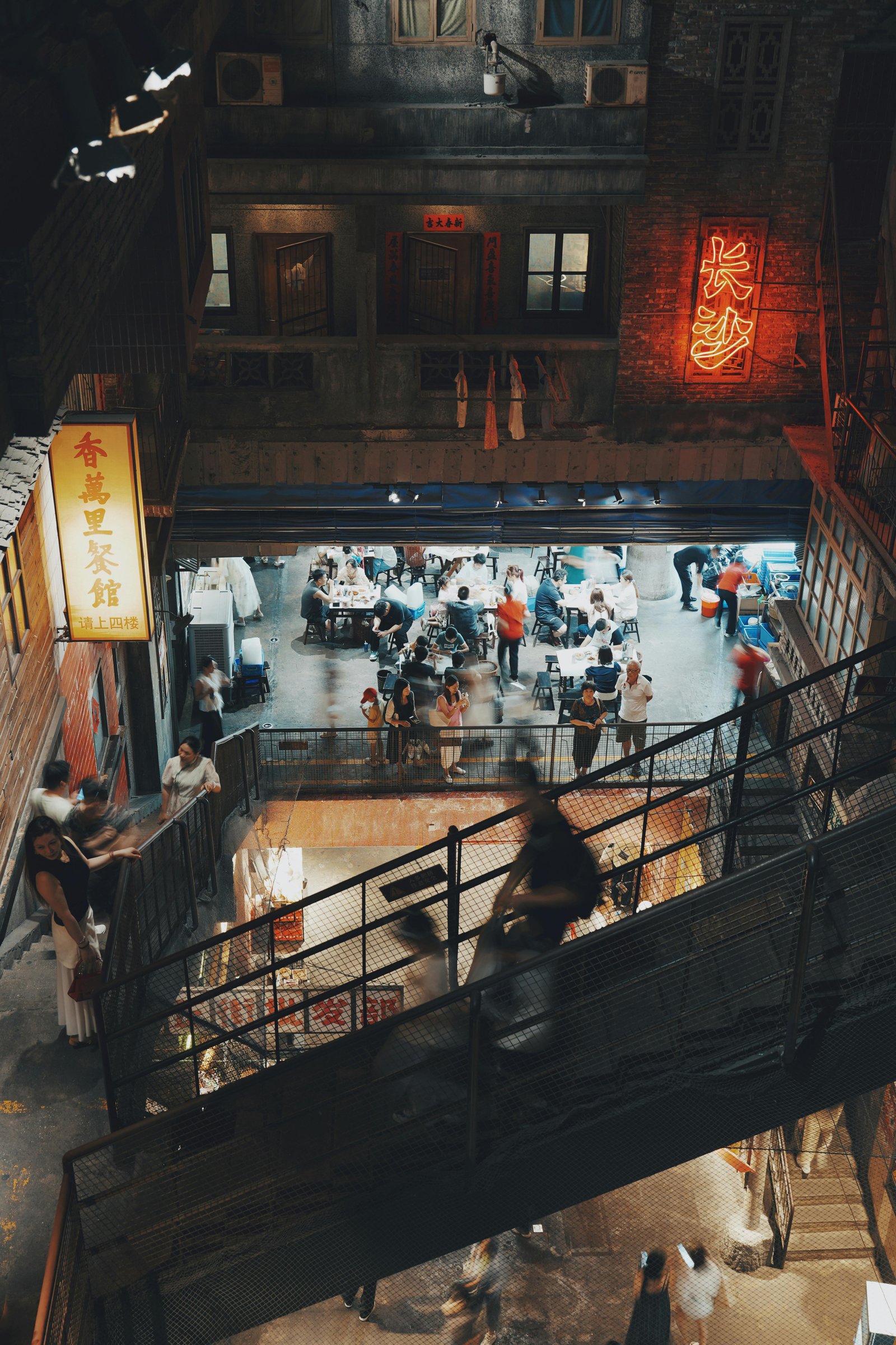 Vibrant indoor market featuring neon lights, dining area, and people socializing.